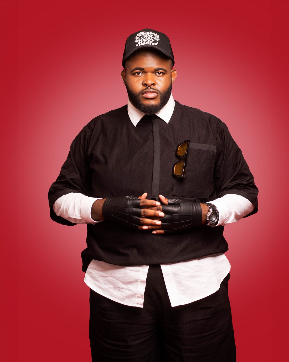 Jay standing with gloved hands clasped against a red wall